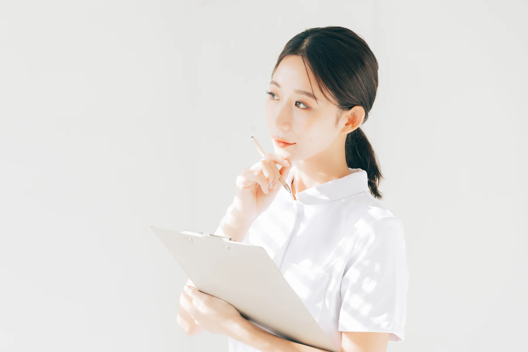 カルテを持って考える看護師